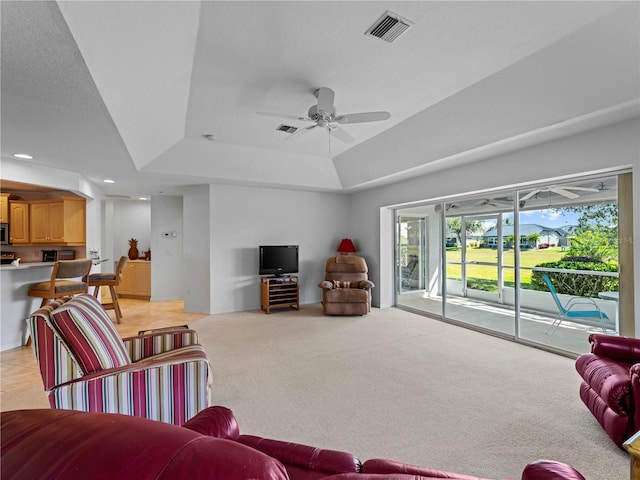 living room featuring light carpet, visible vents, a ceiling fan, a tray ceiling, and recessed lighting