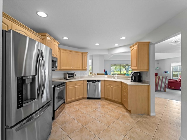 kitchen with light tile patterned flooring, appliances with stainless steel finishes, light countertops, and light brown cabinetry