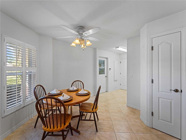 dining area featuring light tile patterned flooring, a ceiling fan, and baseboards