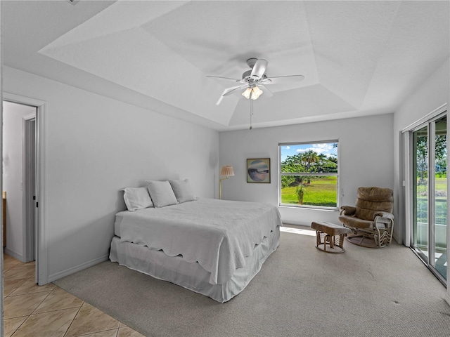 bedroom with light tile patterned flooring, a ceiling fan, baseboards, access to exterior, and a tray ceiling