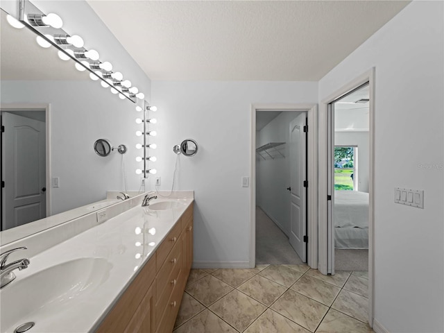 full bath with tile patterned flooring, a sink, baseboards, and double vanity