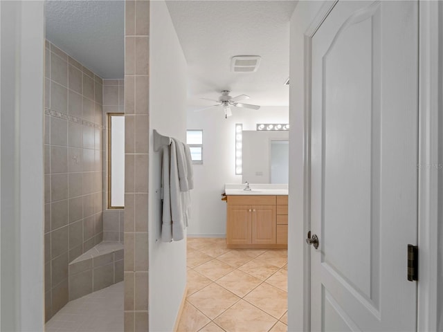 full bath featuring ceiling fan, vanity, a textured ceiling, a walk in shower, and tile patterned flooring