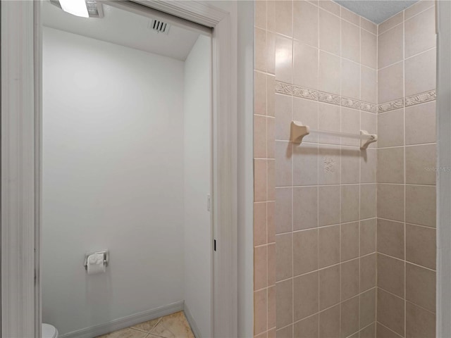 bathroom with tiled shower, tile patterned floors, toilet, and baseboards