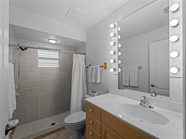 full bathroom featuring a tile shower, vanity, and toilet