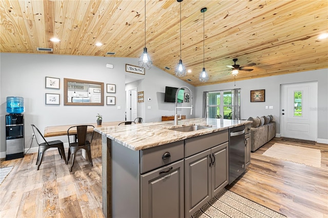 kitchen with an island with sink, open floor plan, hanging light fixtures, light stone countertops, and gray cabinetry