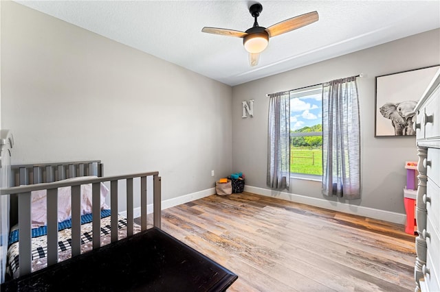 bedroom with light wood-style flooring, baseboards, and a textured ceiling