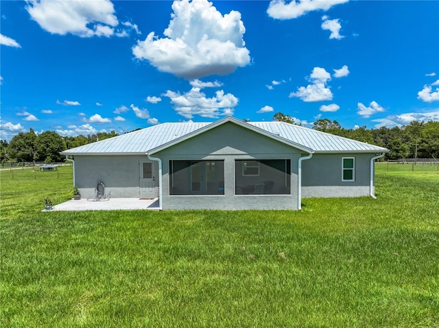 back of house featuring stucco siding, a lawn, a sunroom, a standing seam roof, and metal roof