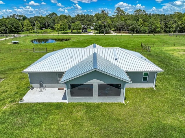 back of property featuring a lawn, metal roof, a water view, a standing seam roof, and fence