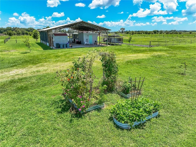 view of yard featuring a pole building, a rural view, a vegetable garden, and fence