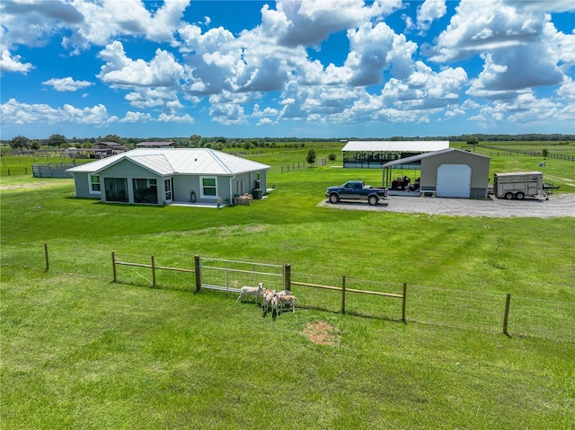 view of yard with a carport, a rural view, fence, and a garage