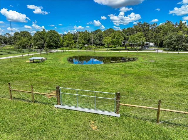 view of home's community featuring a water view, fence, a lawn, and a rural view