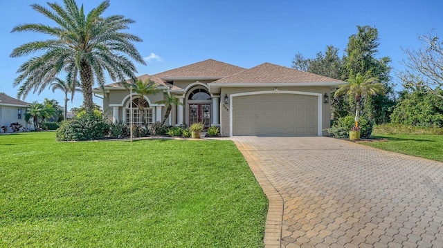 mediterranean / spanish-style home featuring a garage, decorative driveway, a front lawn, and stucco siding