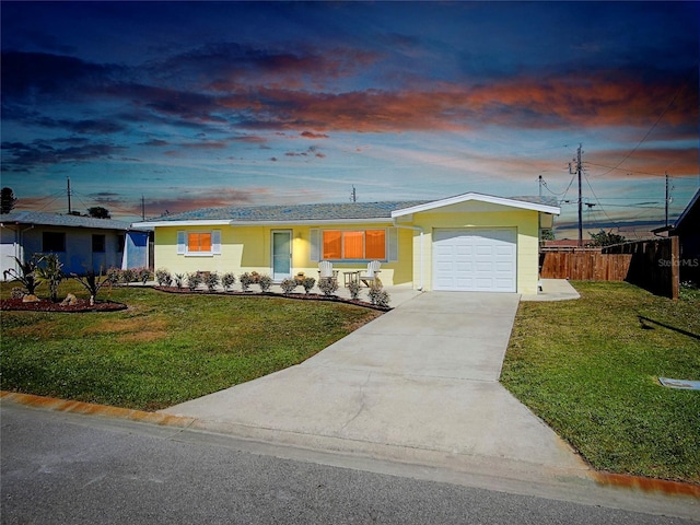 ranch-style house with a front yard, concrete driveway, fence, and an attached garage