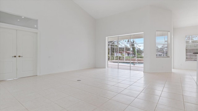 empty room with high vaulted ceiling and light tile patterned flooring