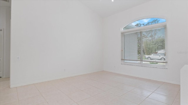 empty room with light tile patterned floors, a wealth of natural light, and baseboards