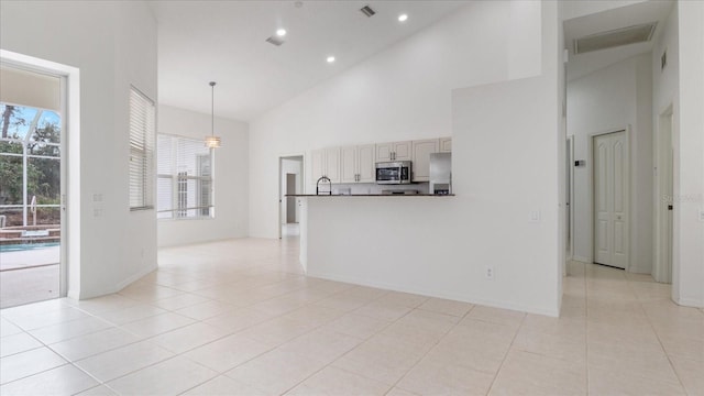 interior space with high vaulted ceiling, visible vents, a sink, and light tile patterned floors