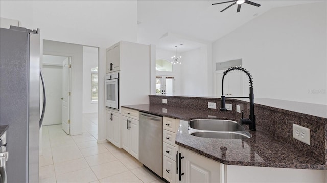 kitchen featuring dark stone counters, ceiling fan, stainless steel appliances, a sink, and light tile patterned flooring