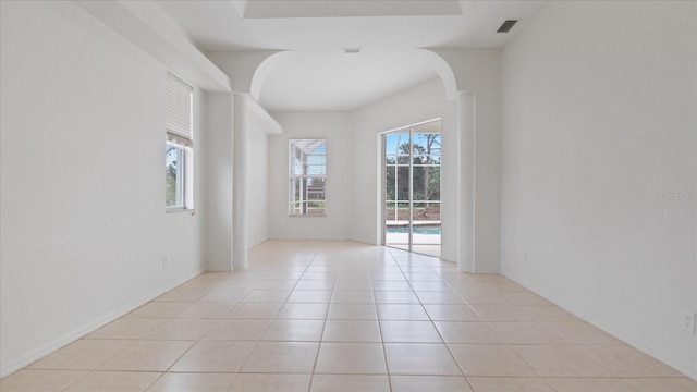 spare room featuring arched walkways, visible vents, and light tile patterned flooring