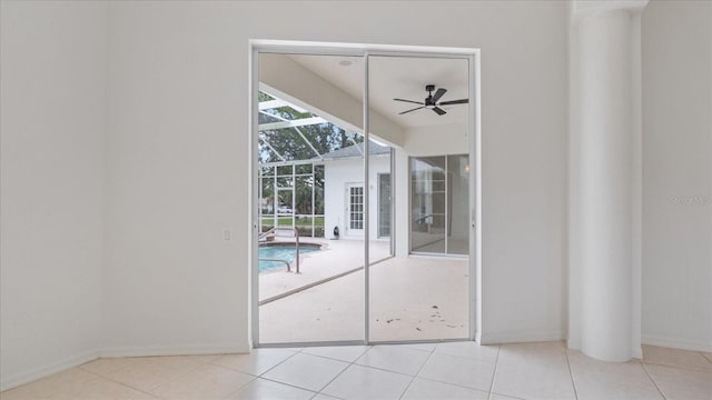 tiled empty room with ceiling fan, a sunroom, and baseboards