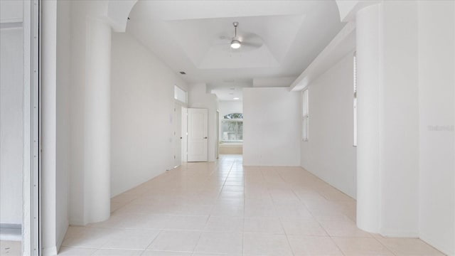 hallway featuring a tray ceiling and light tile patterned flooring