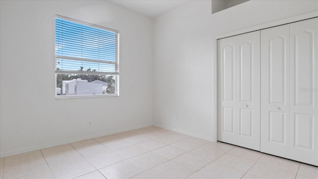 unfurnished bedroom with a closet, baseboards, and light tile patterned floors