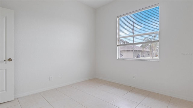 tiled empty room featuring baseboards