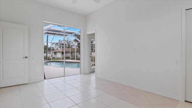 empty room with a ceiling fan, a sunroom, baseboards, and light tile patterned floors