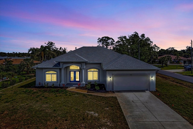 ranch-style home with a yard, driveway, an attached garage, and stucco siding