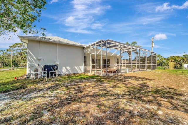 rear view of house with glass enclosure and stucco siding