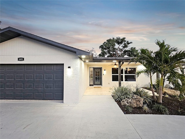 single story home featuring a garage, driveway, and stucco siding