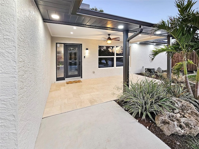 property entrance featuring a patio area, a ceiling fan, and stucco siding