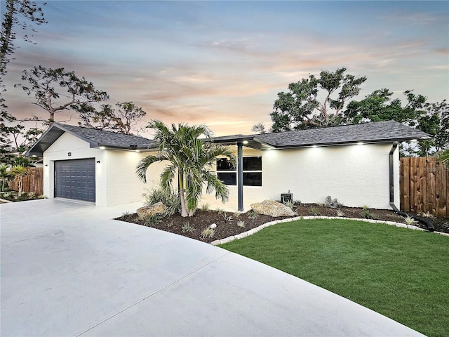 view of front of property featuring an attached garage, a front yard, concrete driveway, and stucco siding