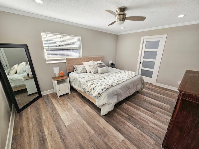 bedroom featuring a textured ceiling, ornamental molding, wood finished floors, and baseboards