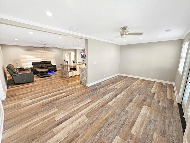 unfurnished living room featuring baseboards, a ceiling fan, light wood-style flooring, ornamental molding, and recessed lighting