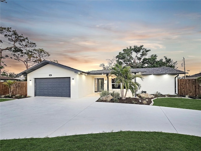 ranch-style house with a garage, driveway, fence, and stucco siding