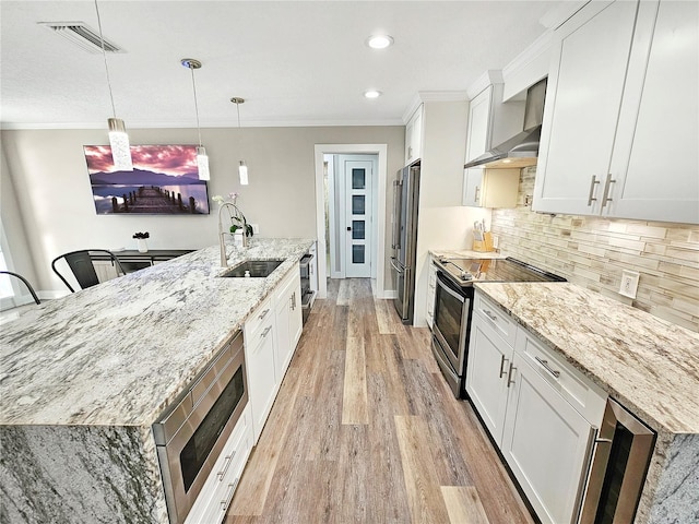 kitchen with stainless steel appliances, a sink, decorative light fixtures, and white cabinets