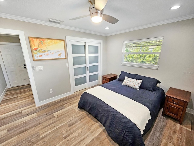 bedroom with baseboards, visible vents, a ceiling fan, crown molding, and light wood-style floors