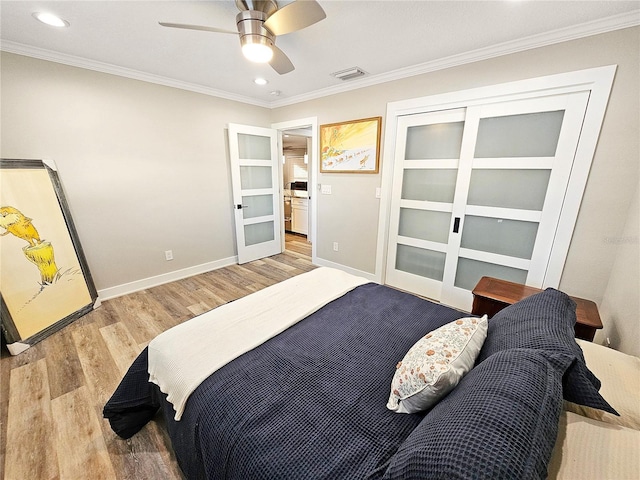 bedroom featuring crown molding, baseboards, visible vents, and light wood-style floors