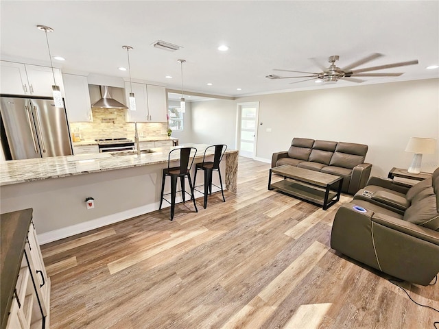 living room with ceiling fan, recessed lighting, visible vents, baseboards, and light wood-type flooring