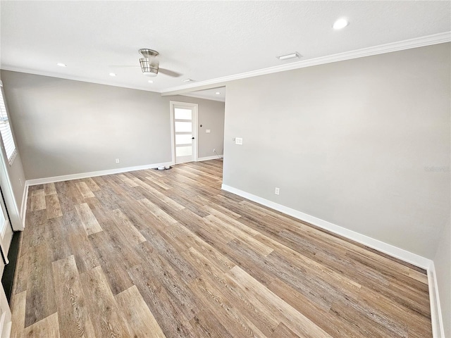 spare room featuring light wood-style flooring, baseboards, and crown molding