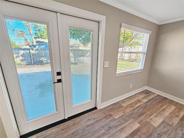 doorway to outside featuring ornamental molding, baseboards, and light wood finished floors