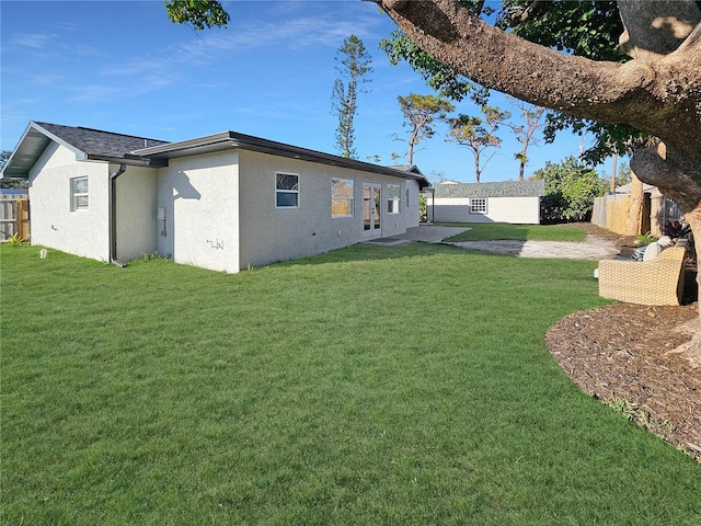 exterior space featuring a lawn, fence, and stucco siding