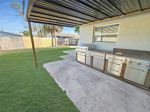 view of patio featuring a fenced backyard, a sink, grilling area, and an outdoor kitchen