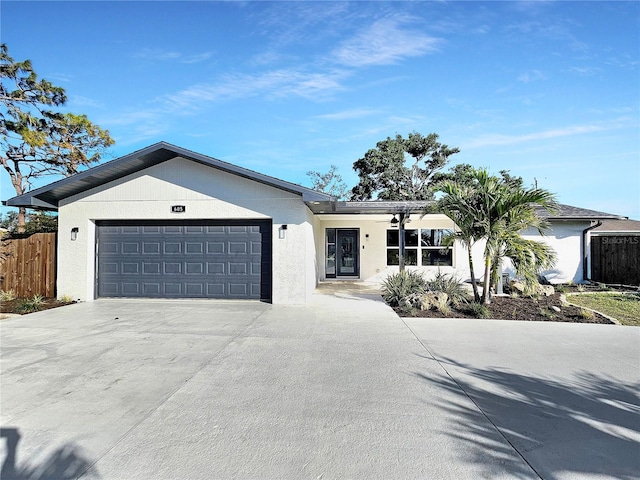 ranch-style house with a garage, concrete driveway, fence, and stucco siding