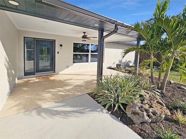 entrance to property featuring ceiling fan, a patio, and stucco siding