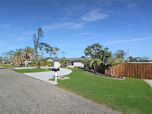 view of front facade featuring driveway, fence, and a front yard