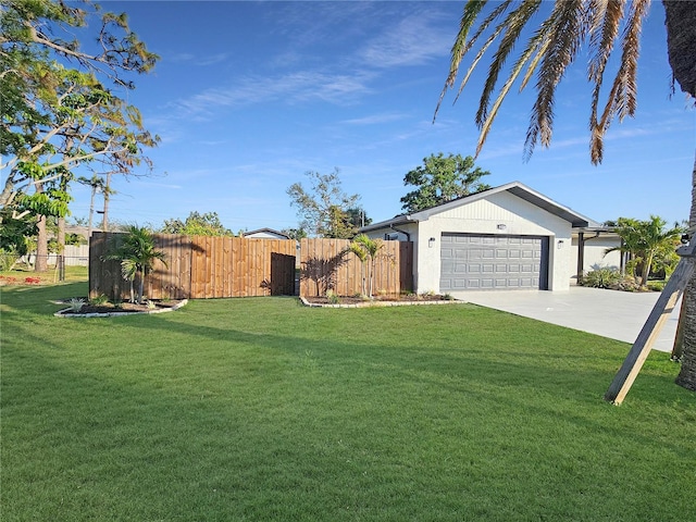 view of yard with concrete driveway, fence, and an attached garage