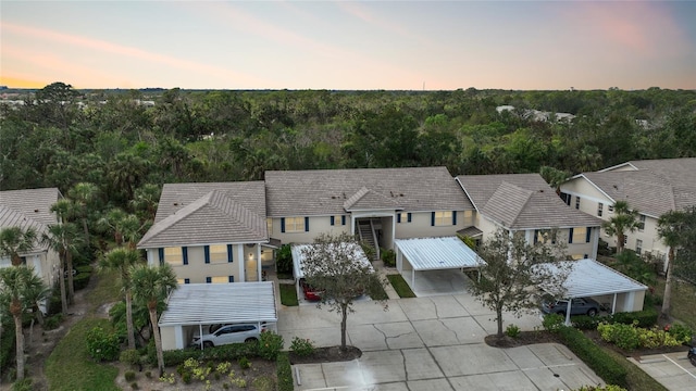 aerial view at dusk featuring a wooded view