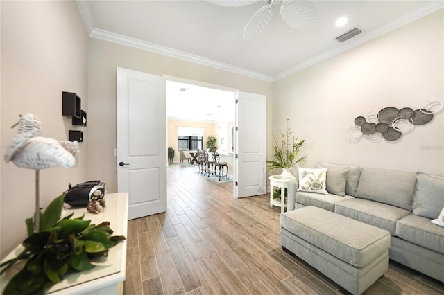 living room featuring ceiling fan, wood finished floors, visible vents, and crown molding