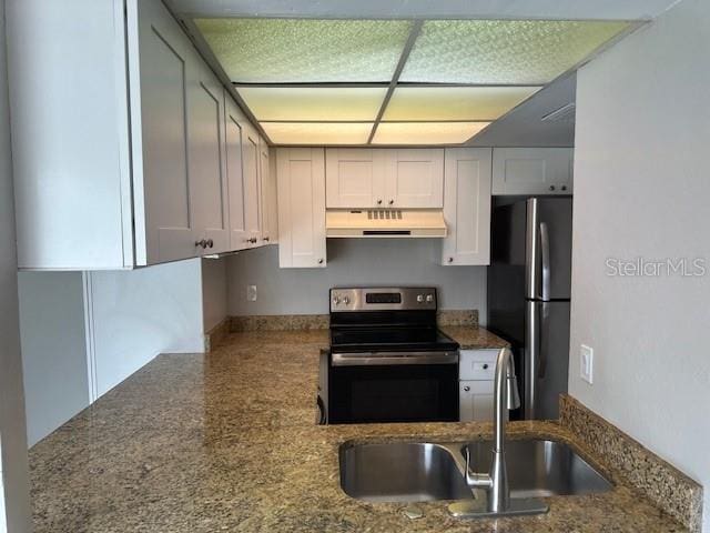 kitchen featuring under cabinet range hood, stone counters, appliances with stainless steel finishes, and a sink